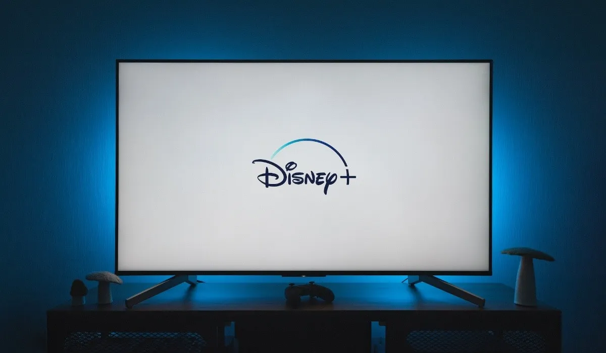 TV a grande schermo sopra un supporto con luce blu dietro in una stanza buia