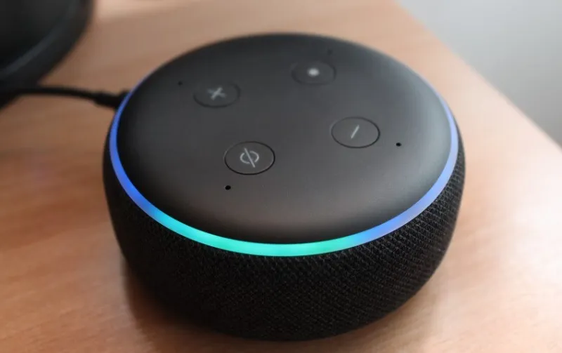 Ein Amazon Echo Dot sitzt auf einem Holztisch.