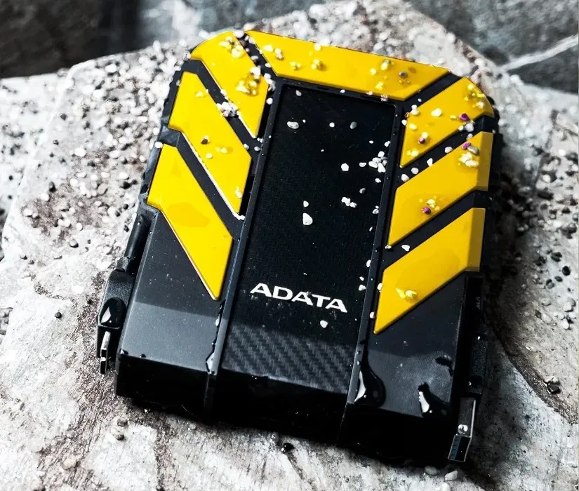 Adata HD710 Pro 2 TB Gelb-schwarze externe Festplatte auf einer weißen Oberfläche im Freien