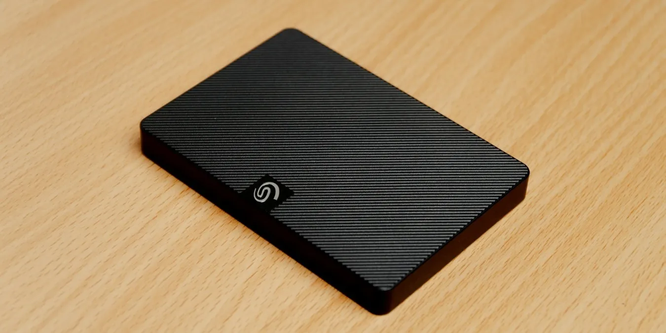 Schwarze externe Festplatte auf einem braunen Schreibtisch