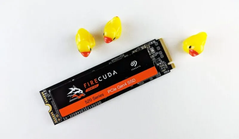 Zbliżenie dysku SSD Seagate obok kilku zabawkowych kaczek na białym tle