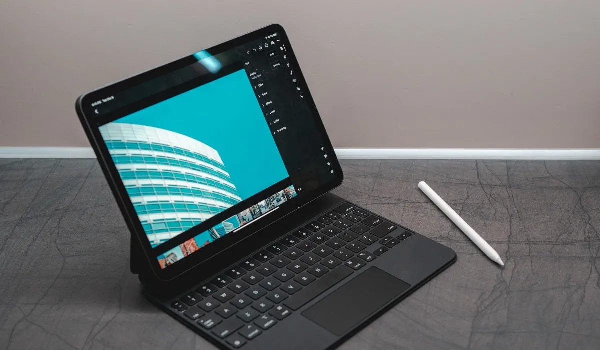 iPad Air nero con tastiera e Apple Pencil su una superficie grigia