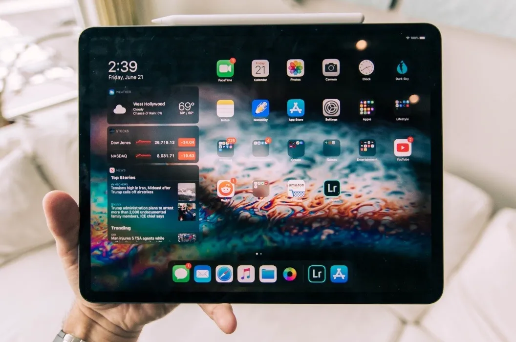 iPad Air noir dans une main sur un arrière-plan intérieur flou