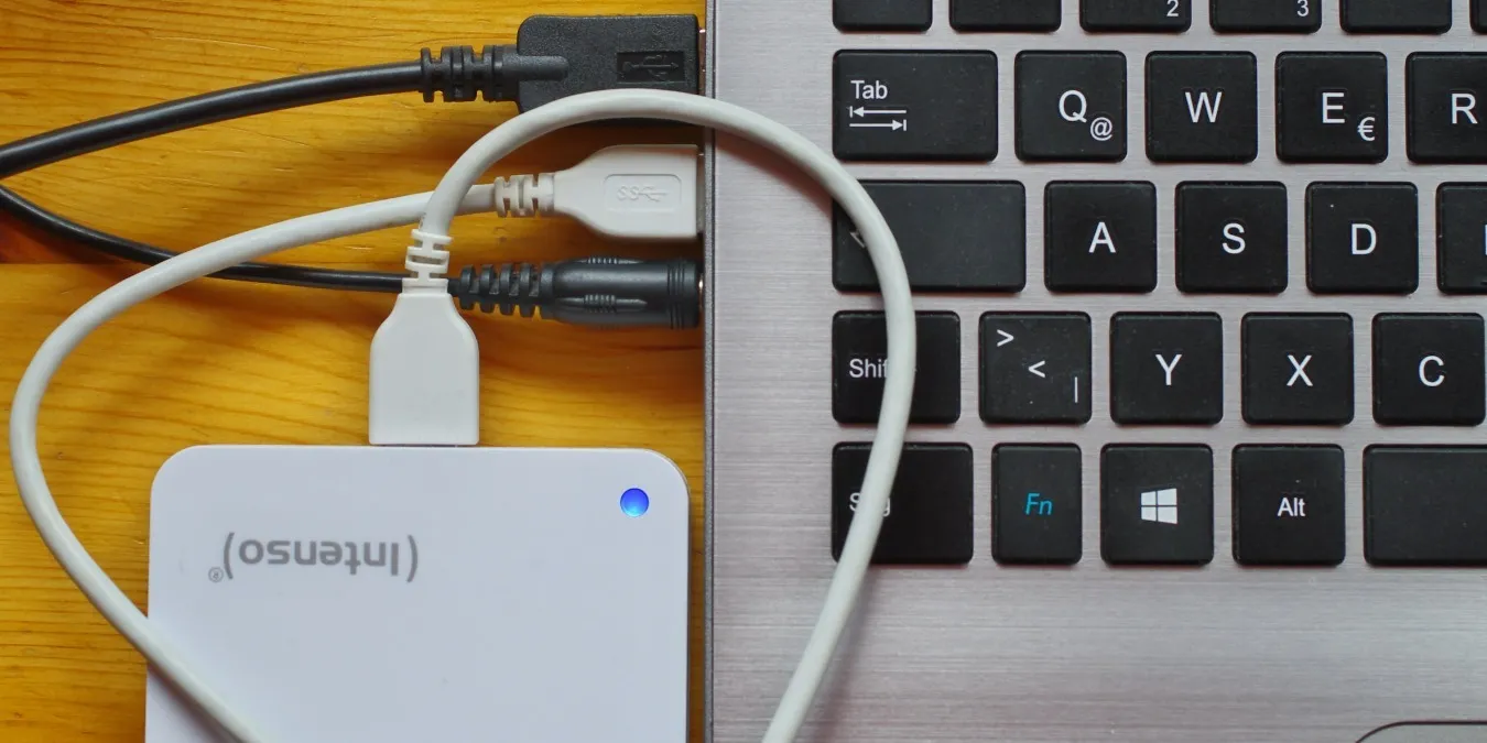 USB-Festplatte, angeschlossen an einen Laptop auf einem braunen Schreibtisch