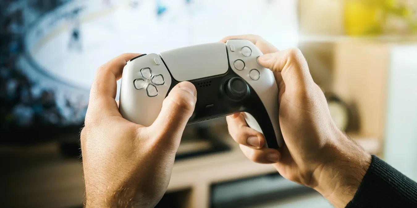 Persoon die PlayStation 5 witte DualSense-controller vasthoudt
