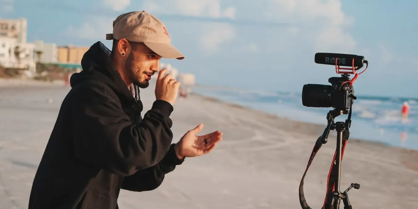 Männlicher Vlogger am Strand, der sich selbst filmt.