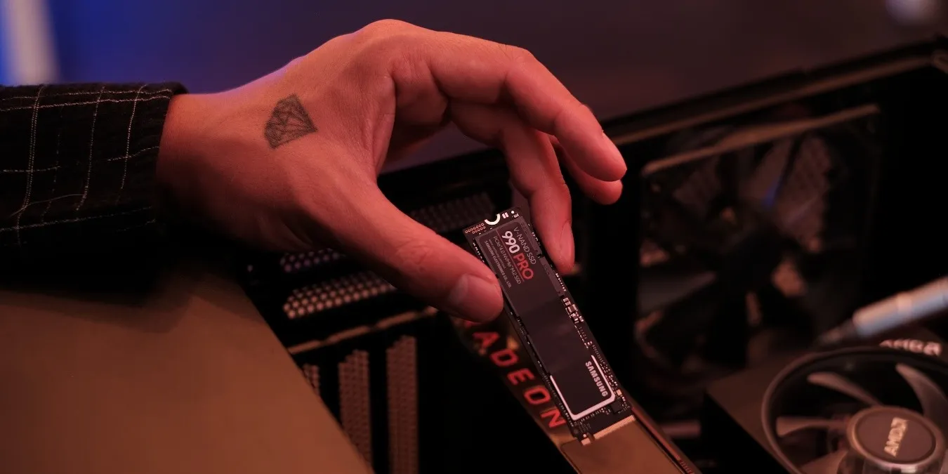 Hand hält eine schwarze Samsung-SSD in der Nähe eines offenen PCs