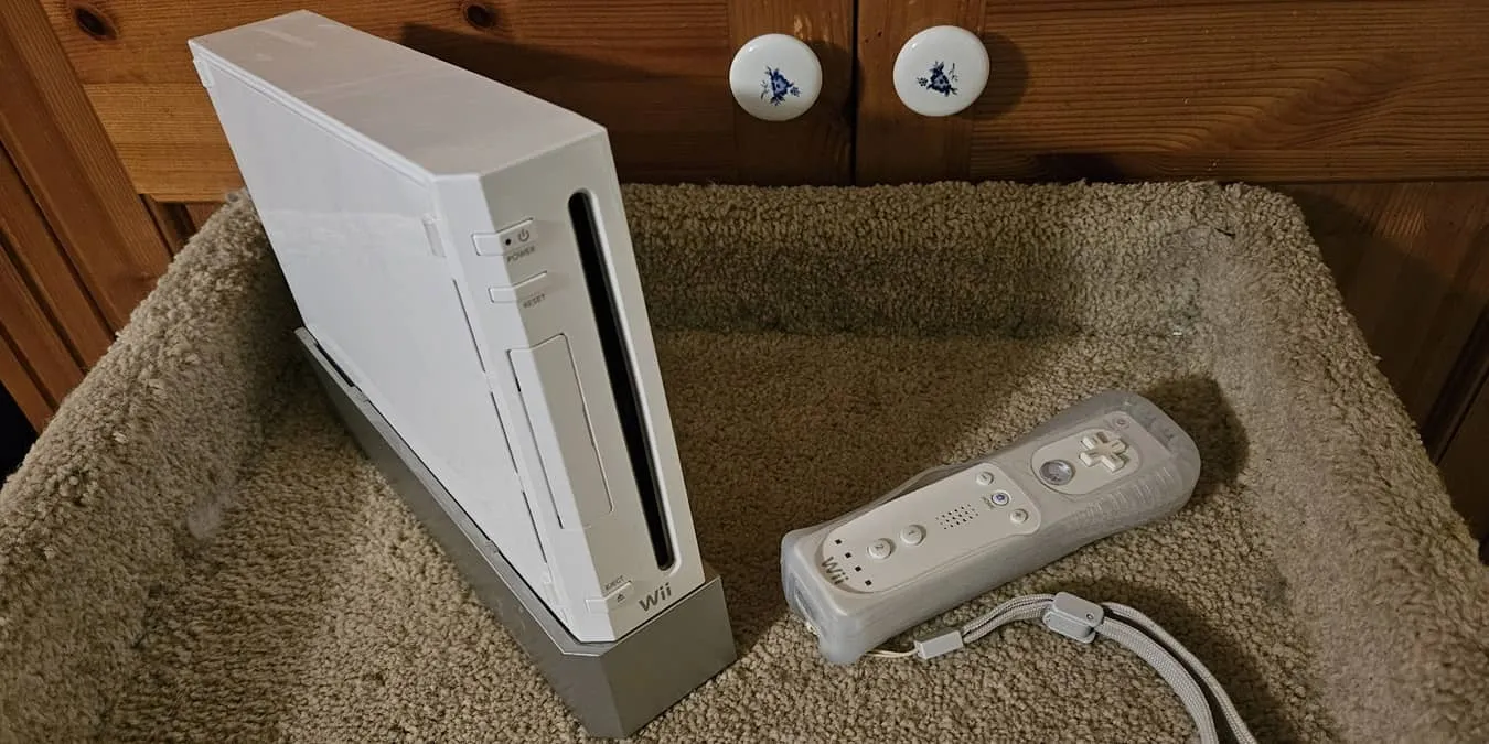 Nintendo Wii com controle em frente a um armário.
