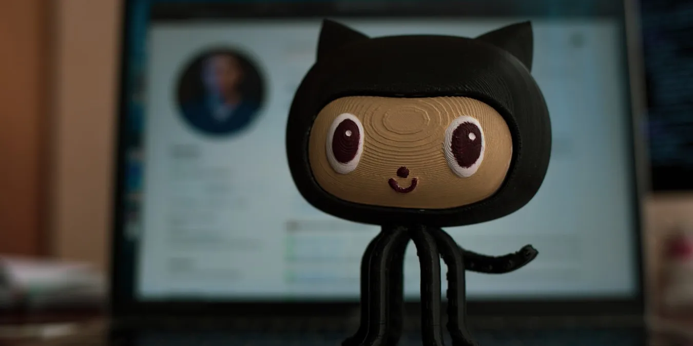 Uma fotografia do mascote do Github na frente da página do Github.