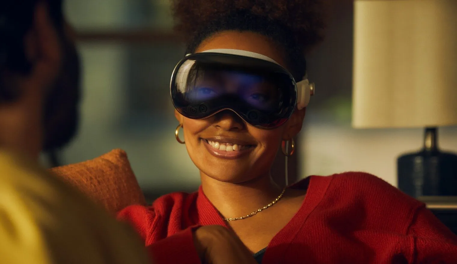 Lächelnde Frau, die das Apple Vision Pro im Passthrough-Modus trägt. Sie können ihre Augen auf dem äußeren Bildschirm des Geräts sehen.