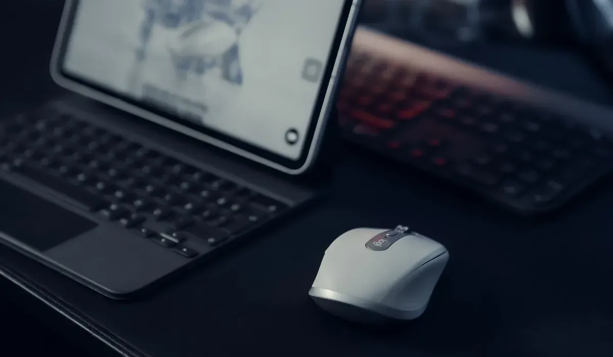 Ratón Bluetooth al lado de una computadora portátil