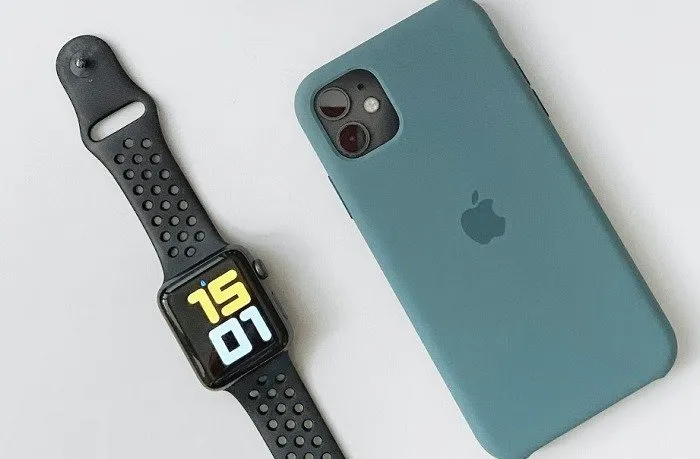 Telefon Apple i zegarek siedzą obok siebie.