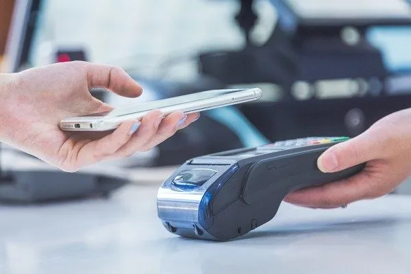 Person scannt ihr iPhone an einem Zahlungsterminal.