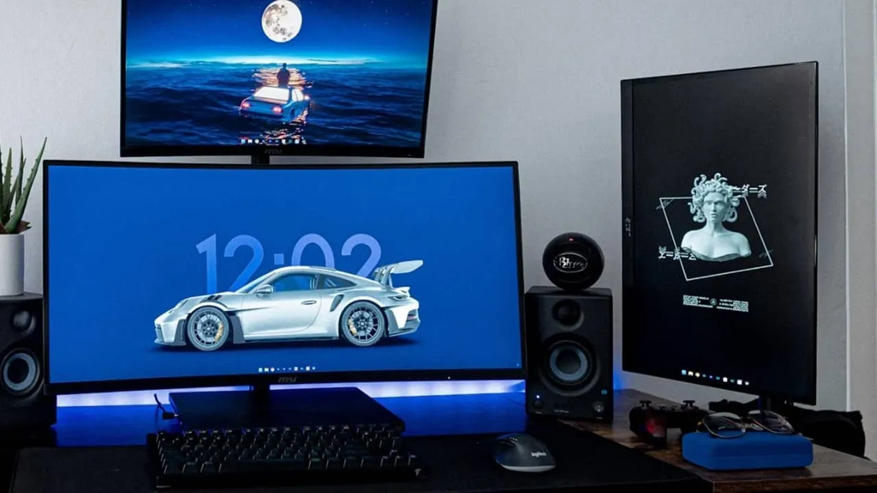 Drie monitoren opstelling op een desktop met toetsenbord.