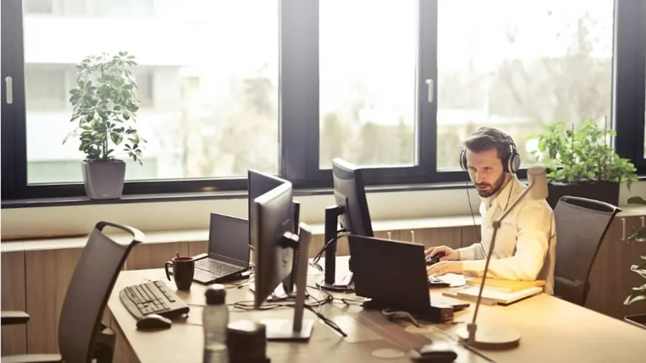 Hombre con auriculares usando una computadora en una oficina.