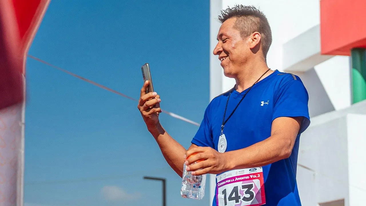 Una maratona che corre guardando il cellulare. Gamification Fitness Allenamento Pexels Latam