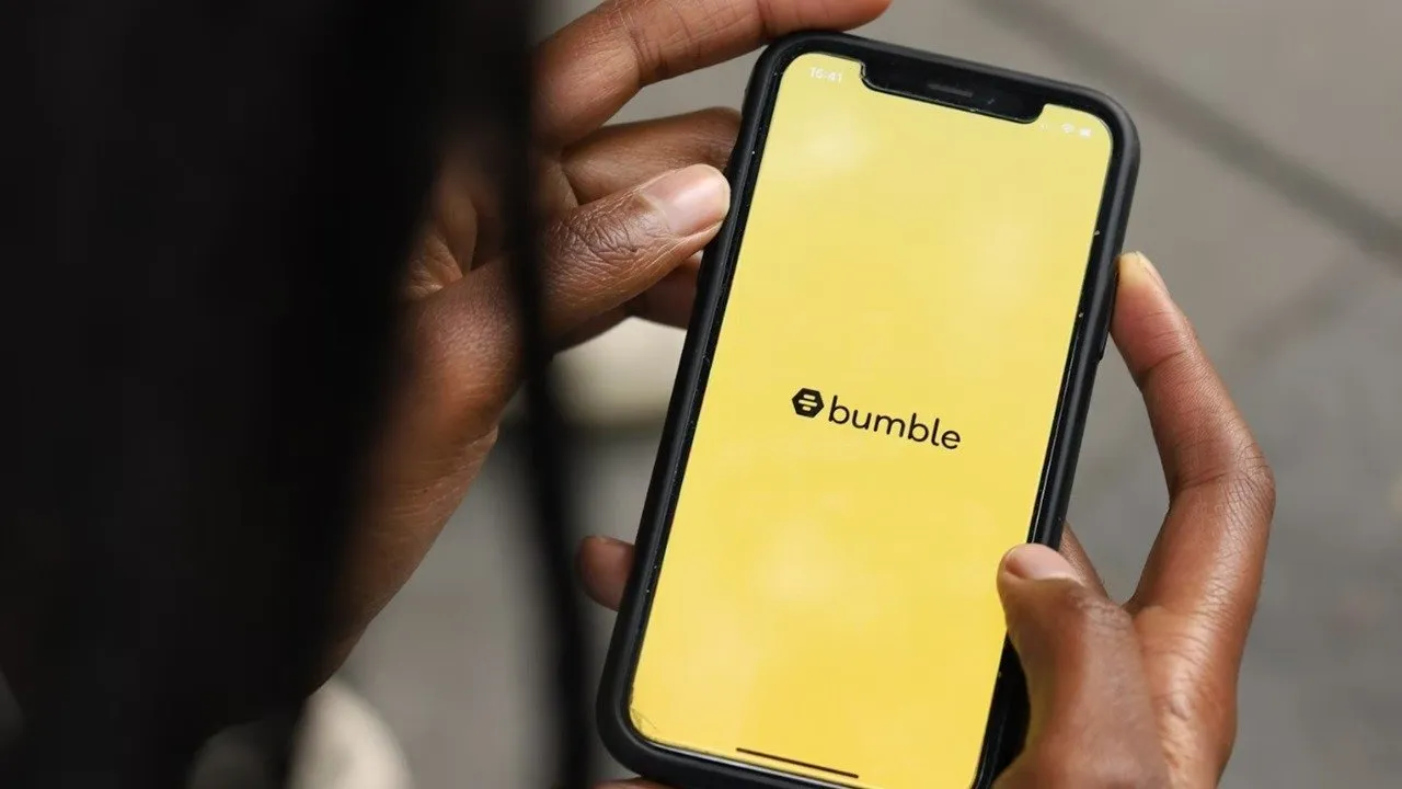 Mão de uma mulher segurando um telefone com o aplicativo Bumble.