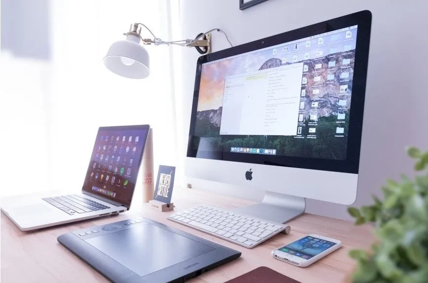 デスクトップ モニター、ラップトップ、タブレット、スマートフォンがすべて机の上に置かれています。