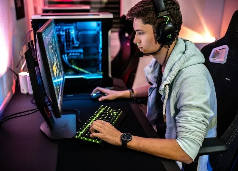 Person trägt Kopfhörer und spielt an einem Gaming-PC