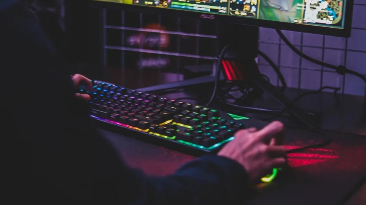 Person, die eine Gaming-Tastatur am Schreibtisch verwendet.