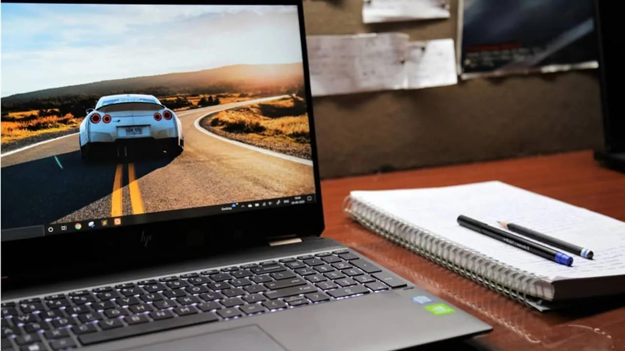 Computadora portátil sentada en un escritorio con un auto deportivo en la pantalla.