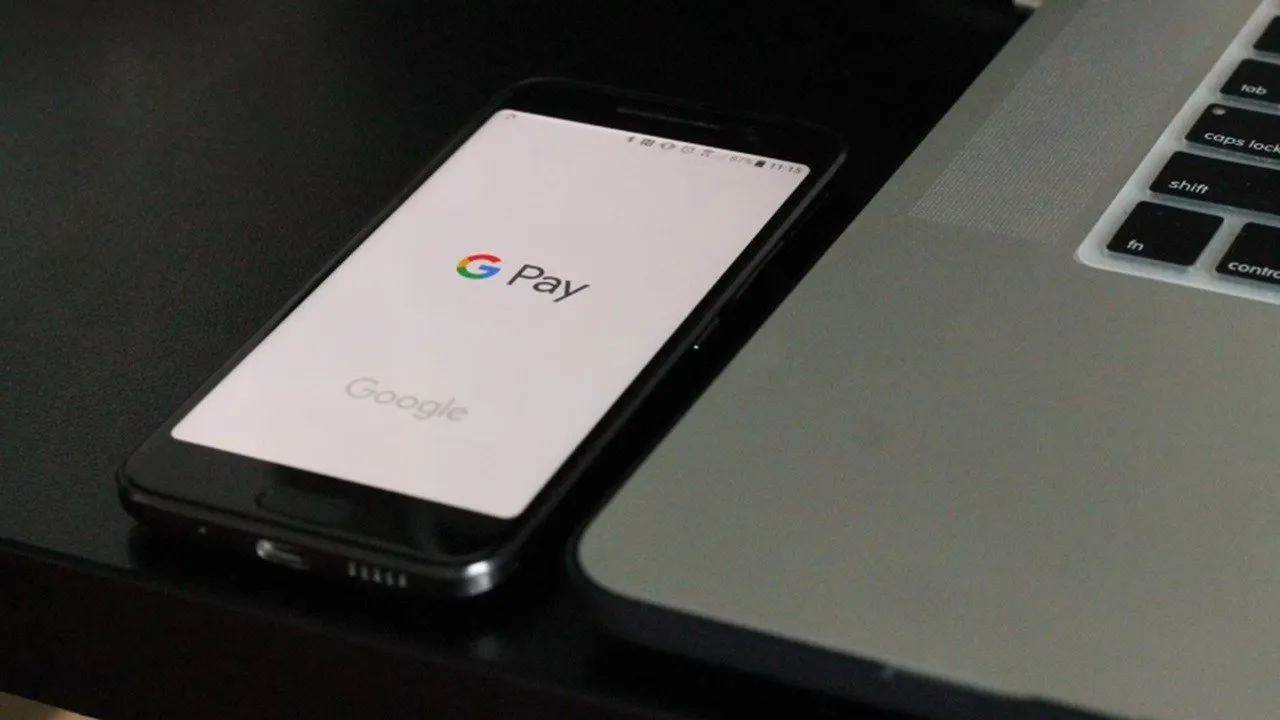 Google Pay wurde auf einem Telefon neben einem Laptop geöffnet.