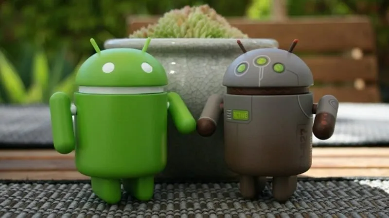 Dos figuras de Android tomadas de la mano una al lado de la otra.
