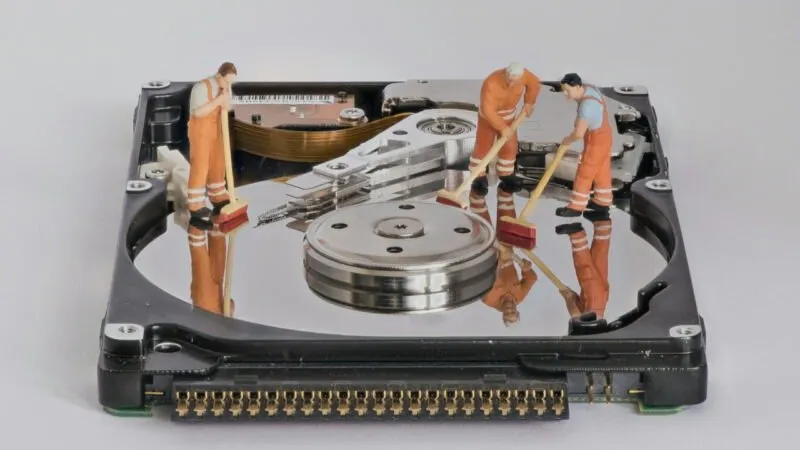 Fotografía de un disco duro delgado con figuras en miniatura encima.