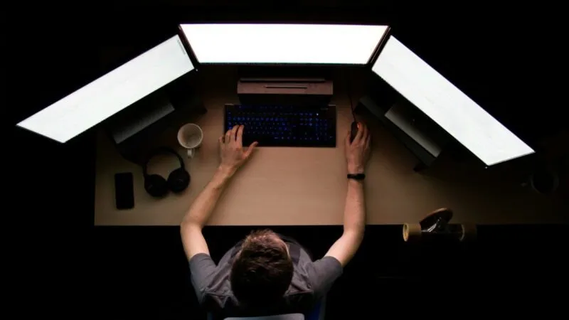 Zdjęcie osoby pracującej przy biurku komputerowym.