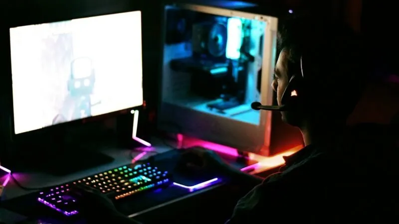 Person mit Kopfhörern, die an einem Gaming-PC spielt