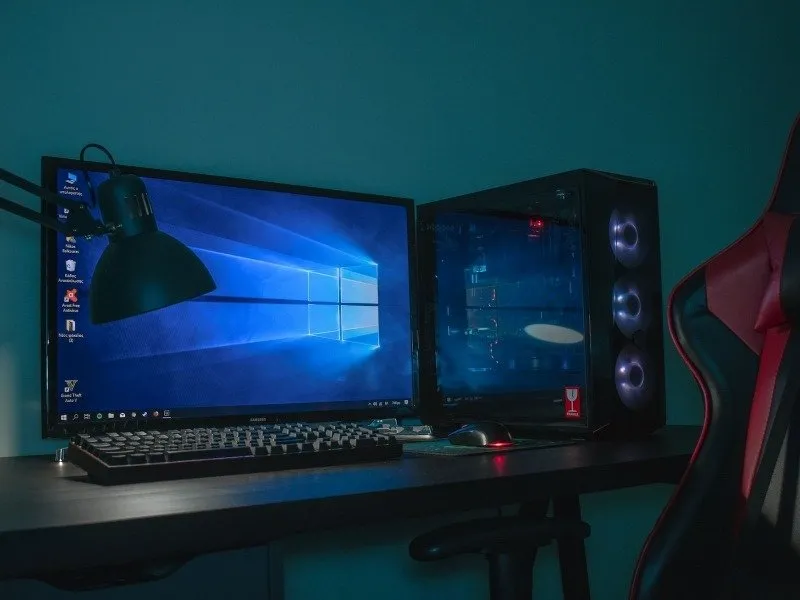 Gaming-PC-Setup auf einem Schreibtisch mit Lampe und Stuhl