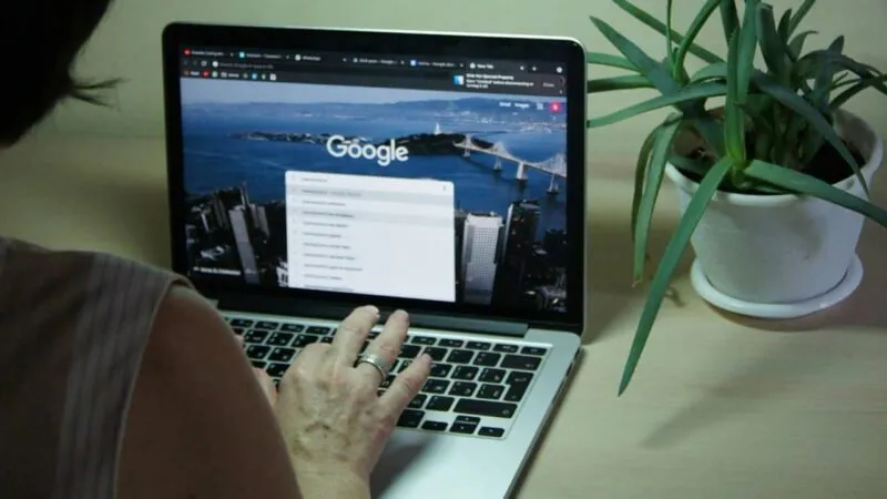 Osoba przeszukująca Google na swoim laptopie.