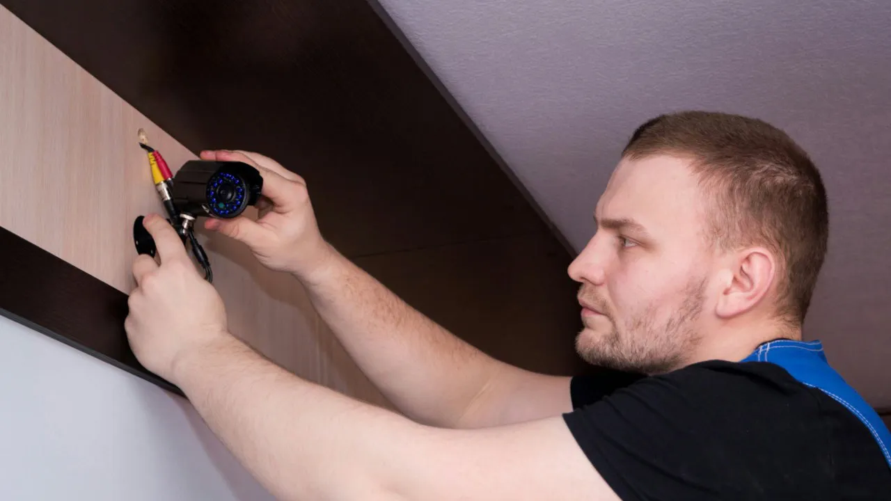 Una fotografía de una persona arreglando una cámara de seguridad.