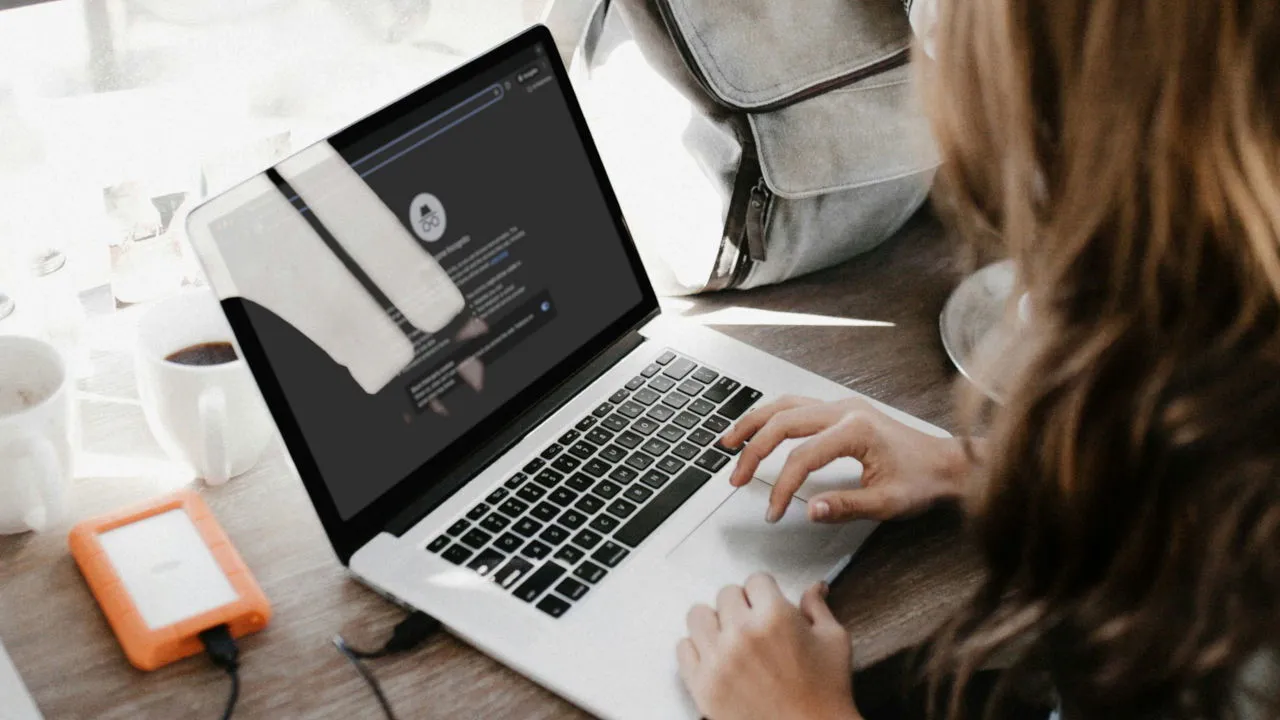 Una fotografía de una mujer usando una computadora portátil sobre una mesa.