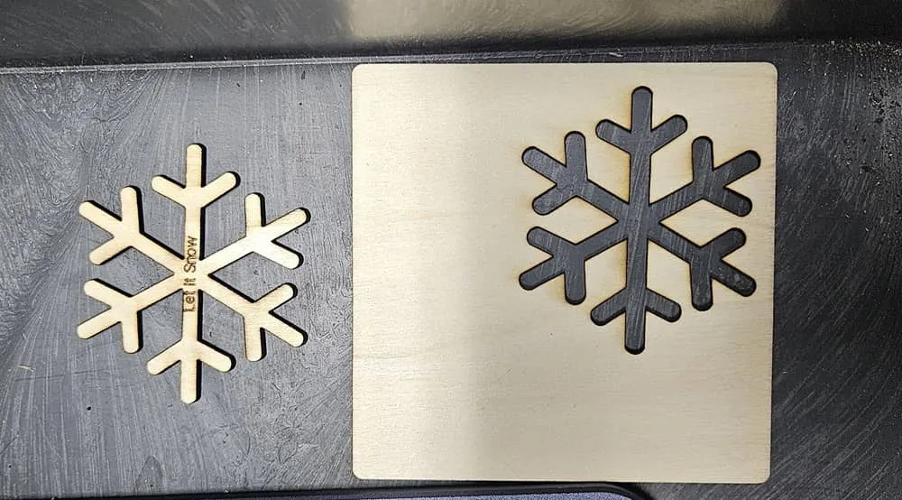 A snowflake cut out of basswood with Let It Snow engraved on it.