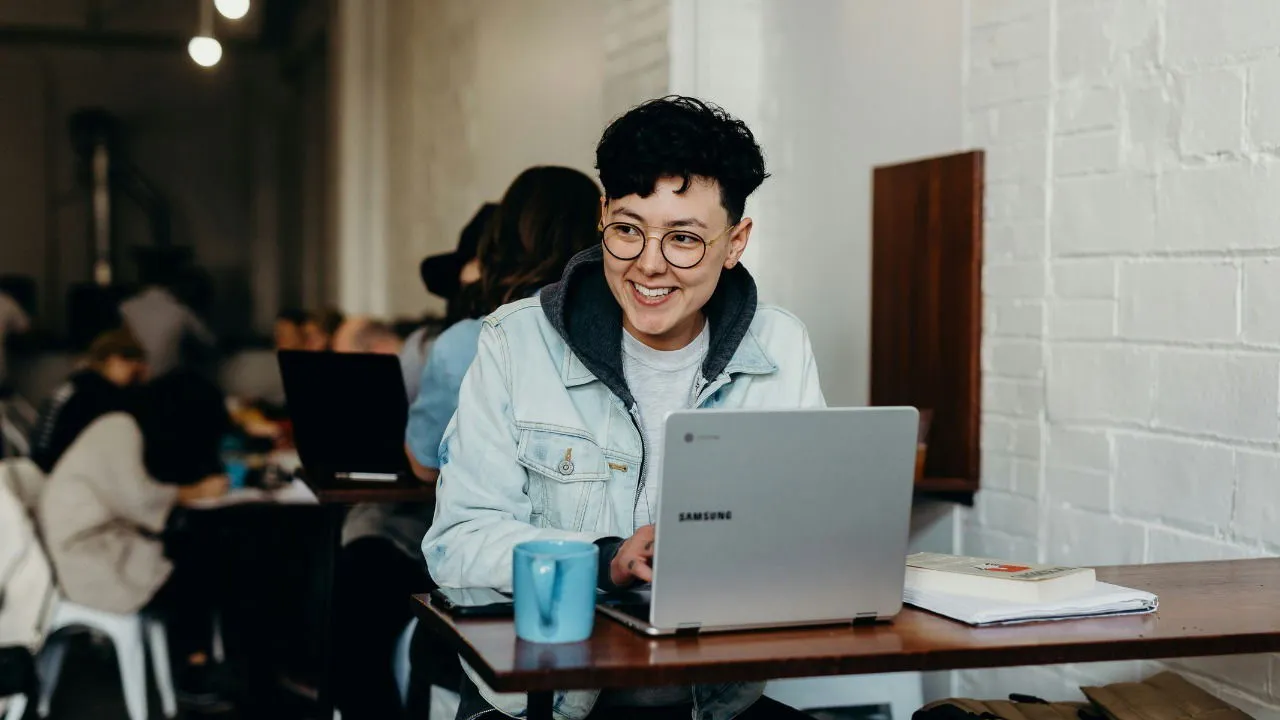 Een persoon die op zijn computer werkt met boeken op tafel