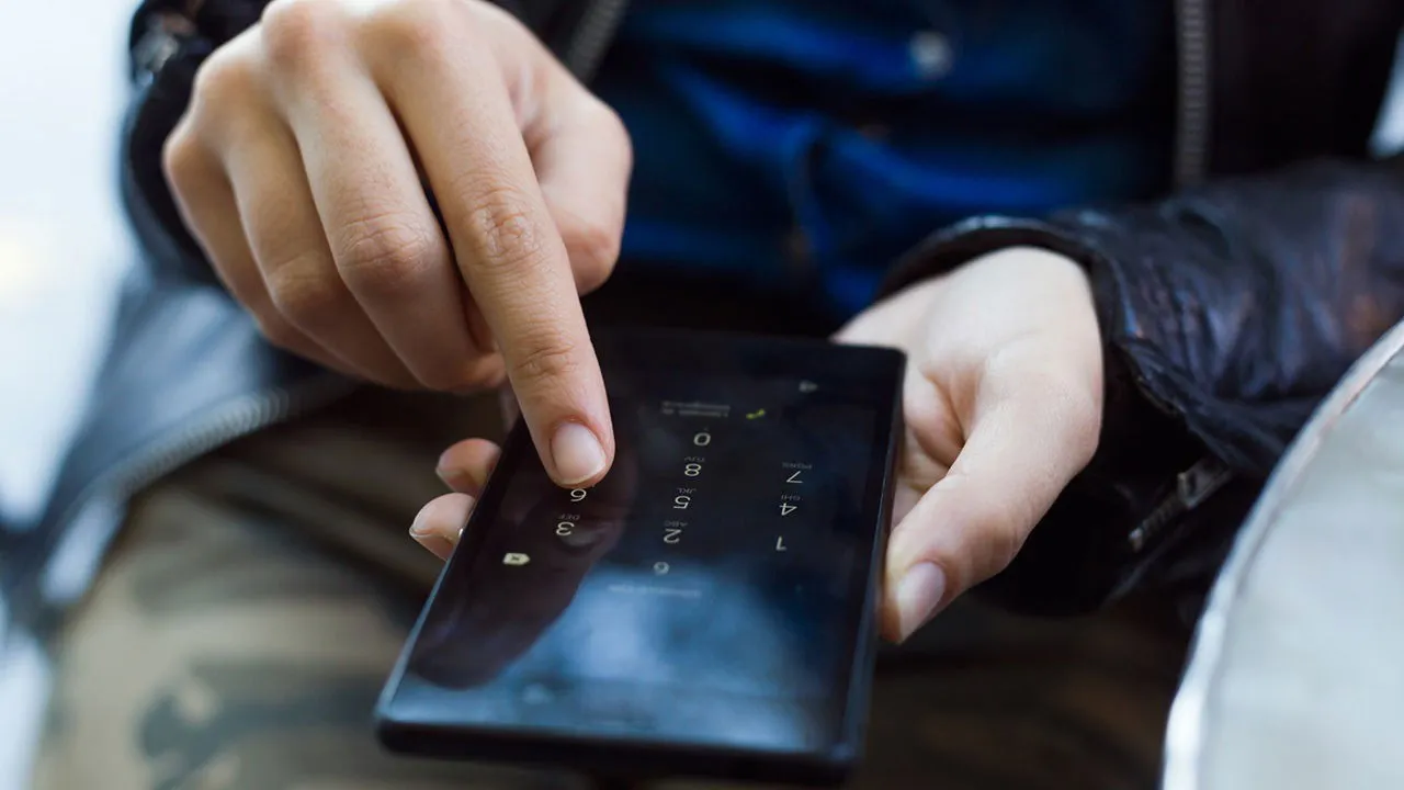 Mooie jonge vrouw gebruikt haar mobiele telefoon op straat.