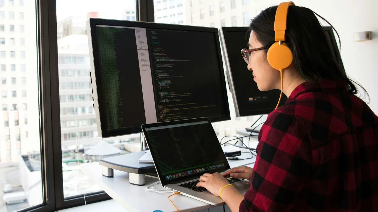 A photograph of a person working in front of a computer.