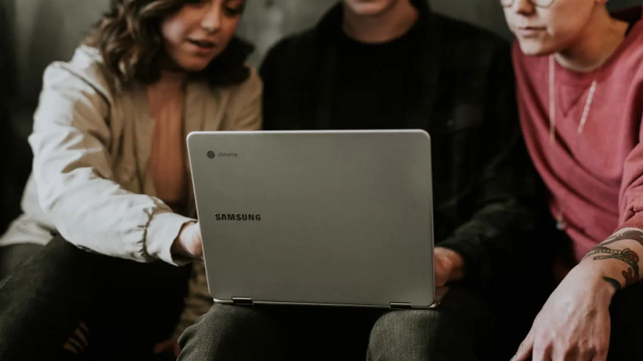 Three individuals engaging with a Chromebook.